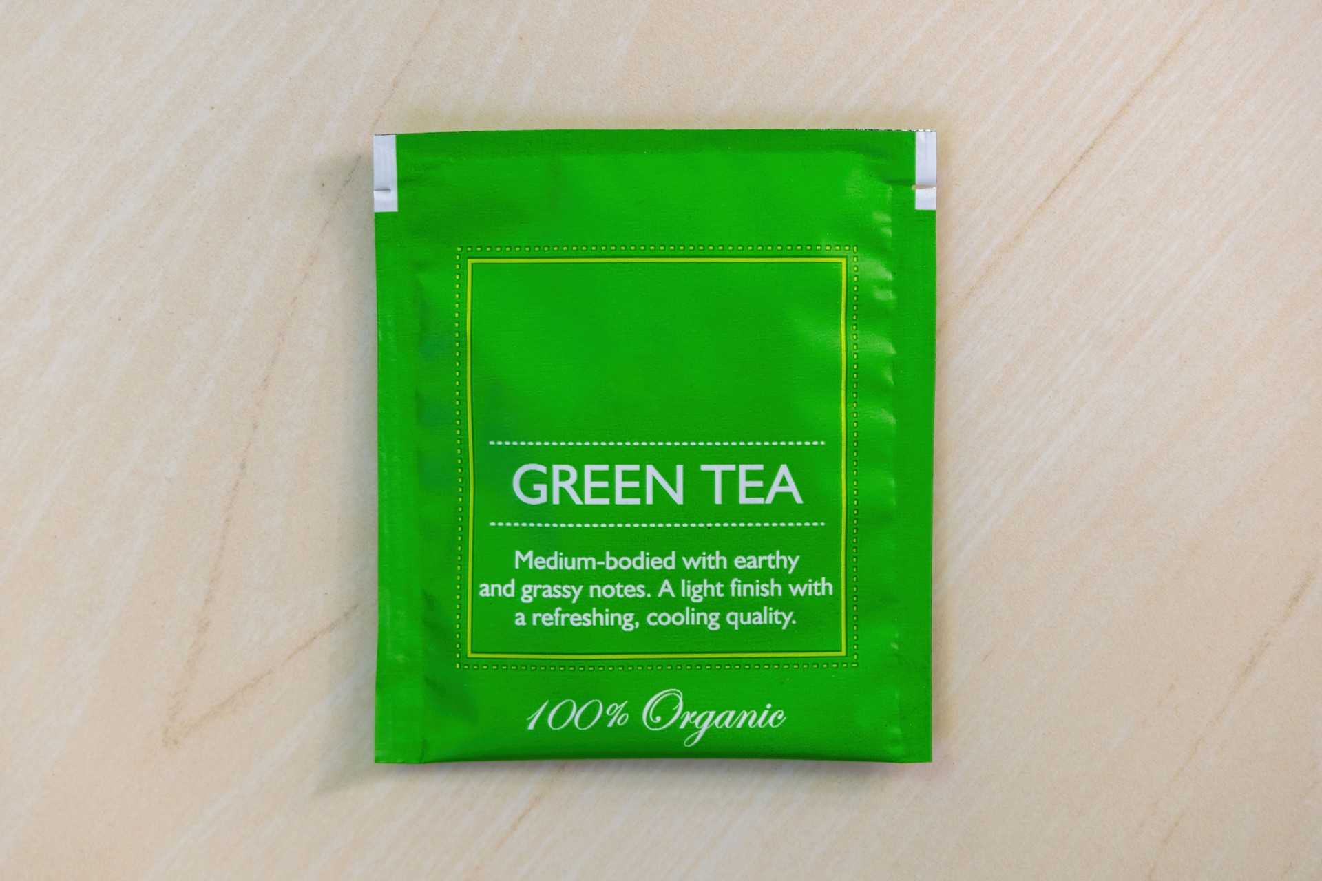 Top view of a green tea bag packet on a wooden background.